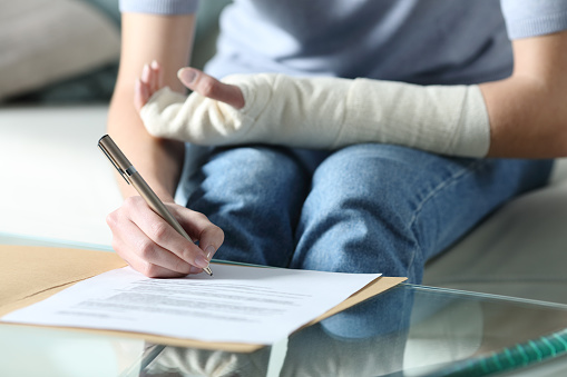 Disabled woman with bandaged arm signing document