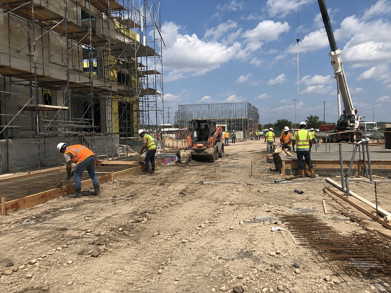 Construction workers pouring concrete and operating heavy equipment on a busy Texas jobsite, illustrating the type of workplace injury that can lead to a non subscriber lawsuit against an employer without workers compensation coverage.